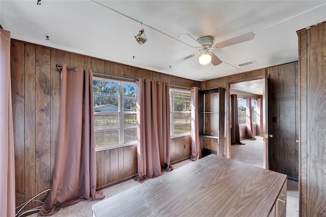 interior space featuring light carpet, ceiling fan, and wood walls