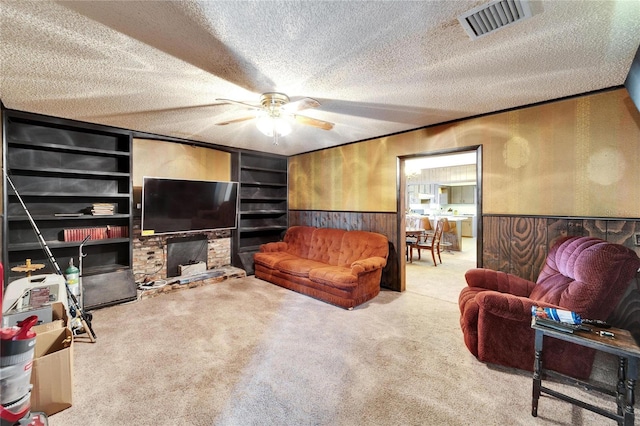 living room featuring a textured ceiling, ornamental molding, wooden walls, built in features, and carpet