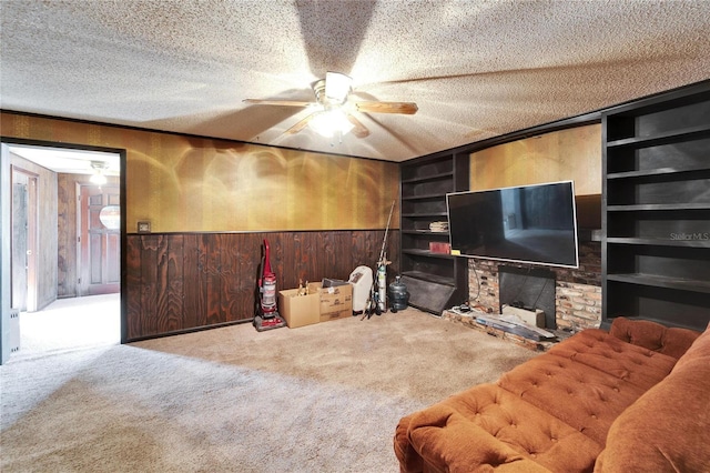 living room featuring built in shelves, light colored carpet, a textured ceiling, and wood walls