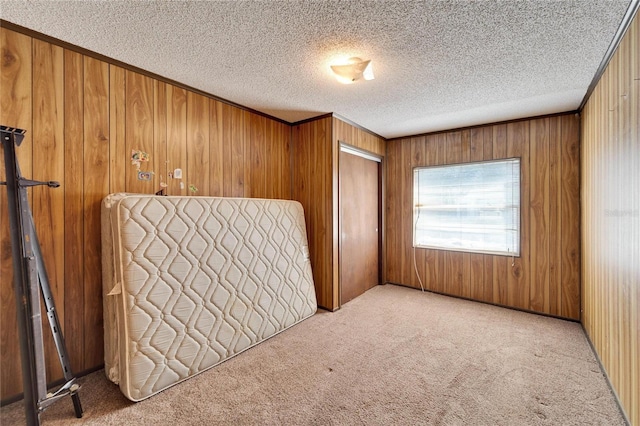 unfurnished bedroom with light colored carpet, a closet, and wood walls