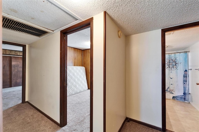 corridor featuring light carpet and a textured ceiling