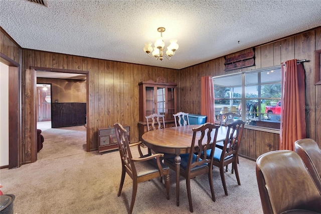 dining area with an inviting chandelier, heating unit, a textured ceiling, light carpet, and wood walls