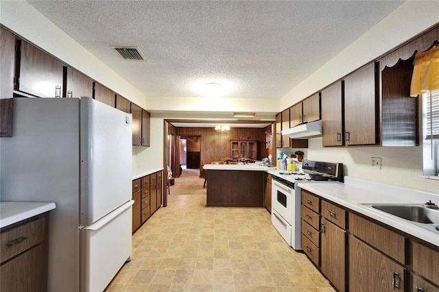 kitchen featuring dark brown cabinetry, a textured ceiling, white appliances, and kitchen peninsula