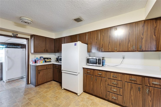 kitchen with white refrigerator, dark brown cabinets, and a textured ceiling