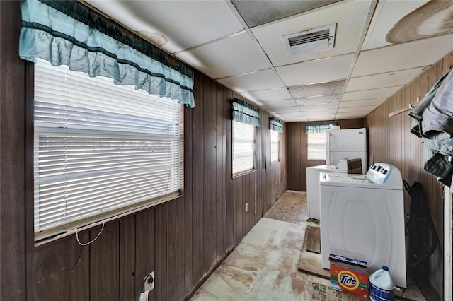 clothes washing area with washer and dryer and wood walls