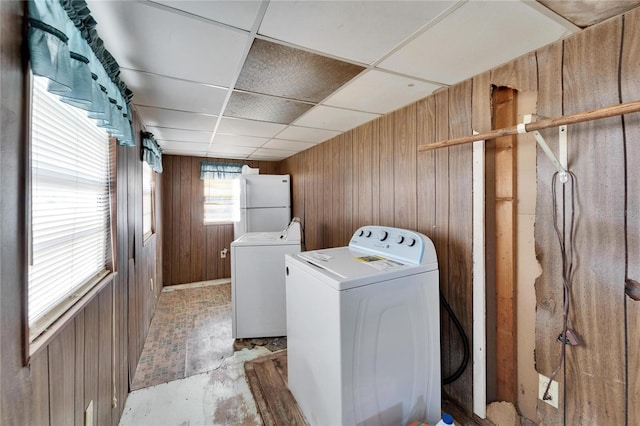 laundry room with separate washer and dryer and wood walls