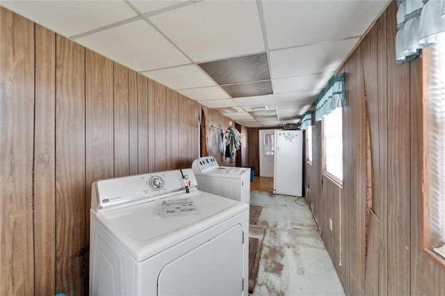 clothes washing area with washer and dryer and wood walls