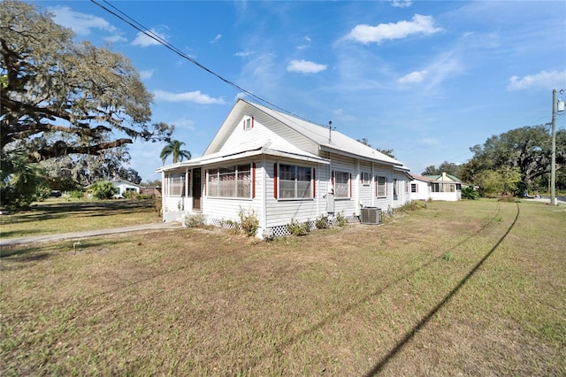 exterior space featuring central AC unit and a front lawn