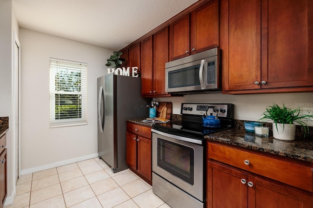 kitchen with dark stone countertops, light tile patterned floors, and stainless steel appliances