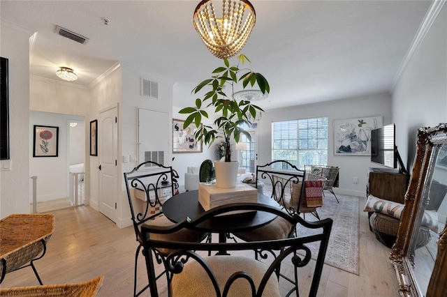 dining room with ornamental molding, a notable chandelier, and light hardwood / wood-style floors