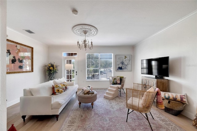 living room with ornamental molding, a chandelier, and light hardwood / wood-style floors