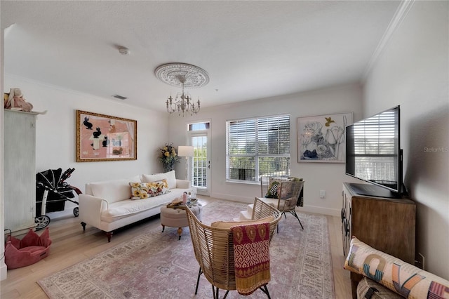 living room featuring ornamental molding, a chandelier, and light hardwood / wood-style floors