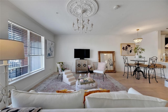 living room with ornamental molding, light wood-type flooring, and an inviting chandelier