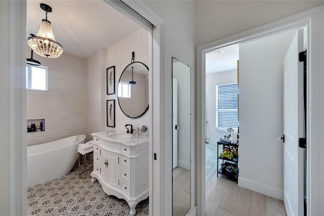 bathroom with hardwood / wood-style flooring, vanity, and a tub to relax in