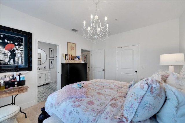 bedroom featuring an inviting chandelier, light hardwood / wood-style floors, and ensuite bathroom