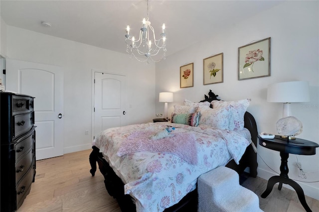 bedroom with a notable chandelier, light wood-type flooring, and a closet