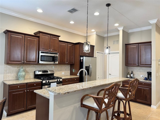 kitchen with light stone counters, appliances with stainless steel finishes, a kitchen breakfast bar, and an island with sink