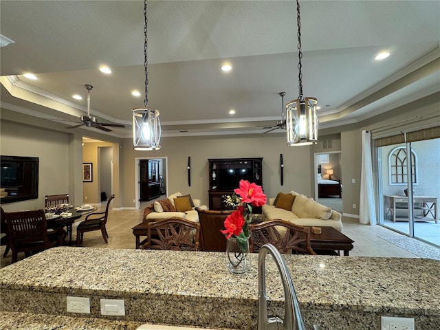 living room with ceiling fan, ornamental molding, a raised ceiling, and sink