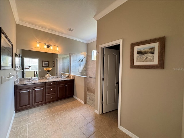 bathroom with crown molding, tile patterned floors, vanity, and a tile shower