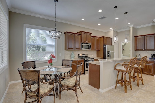 kitchen featuring a breakfast bar area, visible vents, hanging light fixtures, appliances with stainless steel finishes, and light stone countertops