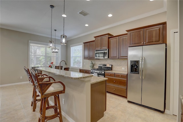 kitchen featuring light stone counters, an island with sink, backsplash, visible vents, and appliances with stainless steel finishes