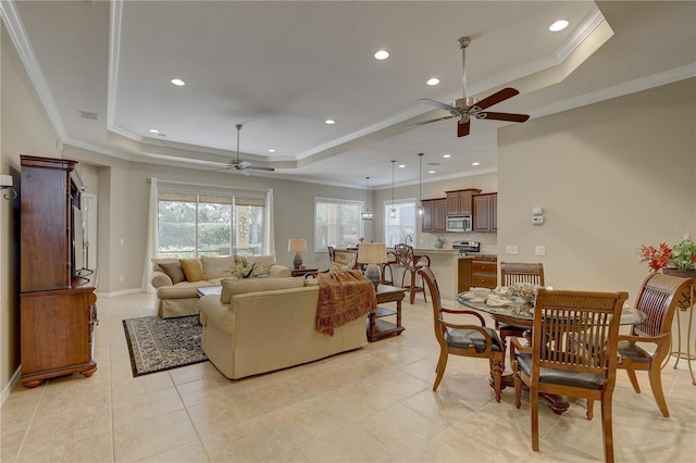 living room featuring a wealth of natural light, ceiling fan, and a raised ceiling