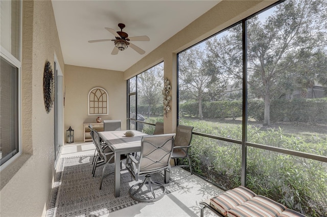 sunroom featuring a ceiling fan and a textured wall