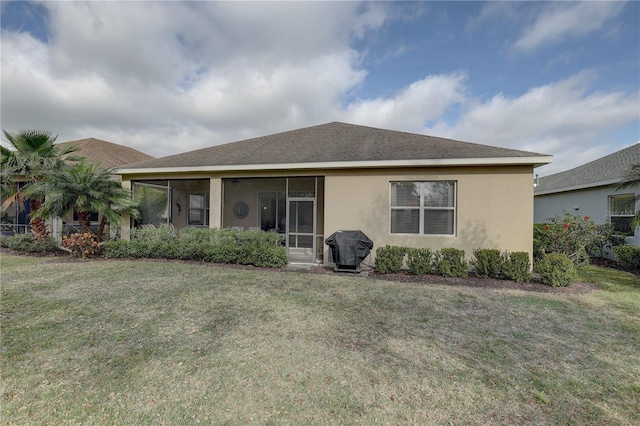 back of property with a yard, stucco siding, a sunroom, and a shingled roof