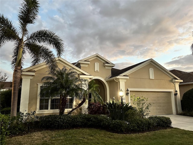 view of front facade featuring concrete driveway, stucco siding, and an attached garage