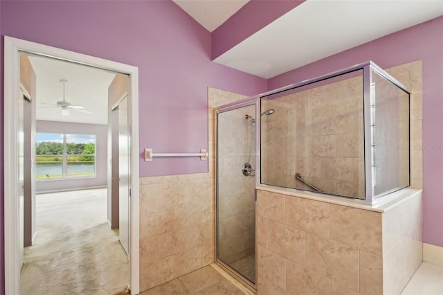 full bathroom featuring ceiling fan, a water view, and a shower stall