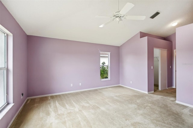 spare room featuring light carpet, lofted ceiling, visible vents, and baseboards