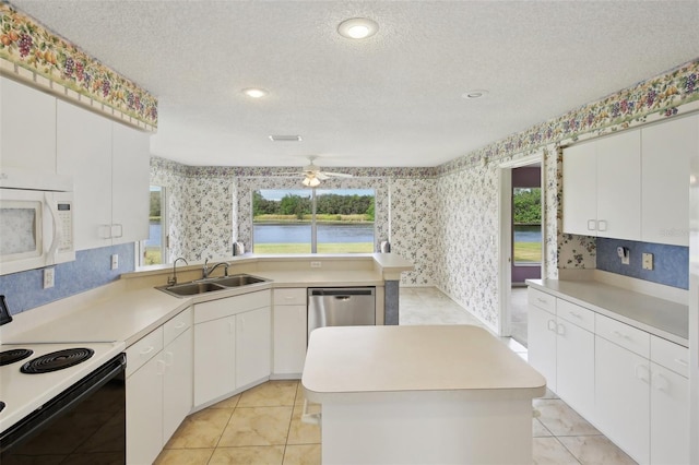 kitchen with a center island, electric range oven, white microwave, a sink, and wallpapered walls