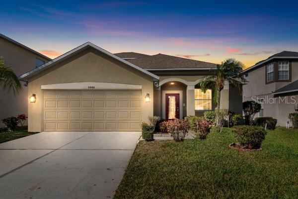 single story home featuring a garage and a lawn