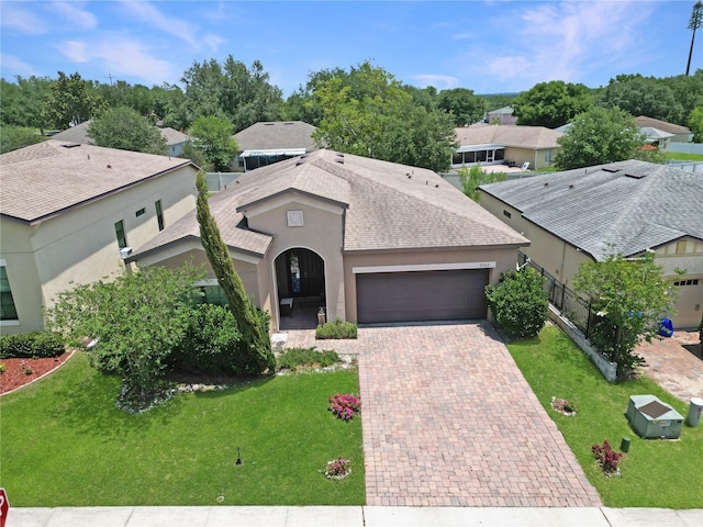 9362 Oglethorpe Dr, Groveland, FL 34736 - view of front of property with an attached garage, decorative driveway, stucco siding, roof with shingles, and a front lawn