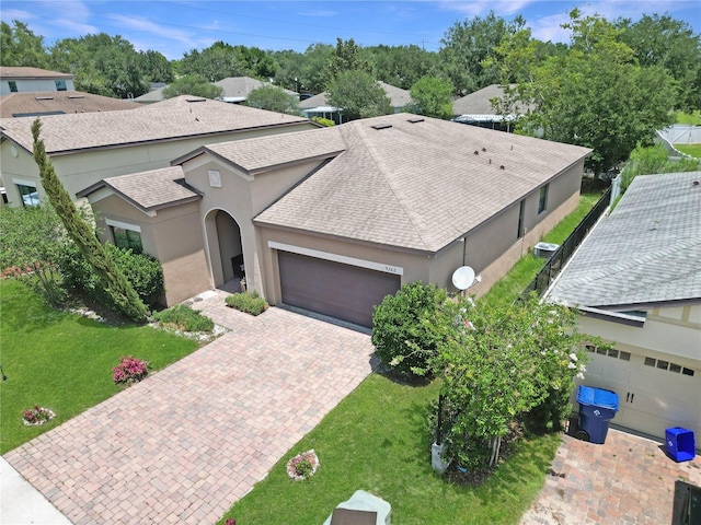 9362 Oglethorpe Dr, Groveland, FL 34736 - view of front of home with roof with shingles, an attached garage, decorative driveway, stucco siding, and a front yard