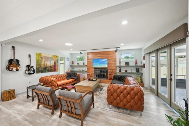 living room featuring wooden walls, light hardwood / wood-style floors, french doors, and track lighting