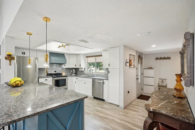 kitchen featuring wall chimney exhaust hood, stainless steel appliances, sink, and white cabinets