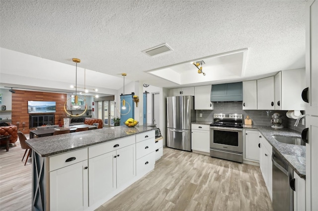 kitchen with sink, white cabinetry, hanging light fixtures, light hardwood / wood-style flooring, and appliances with stainless steel finishes