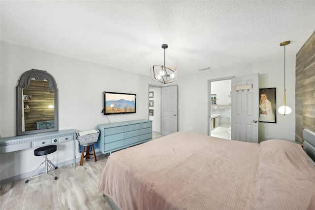 bedroom with light hardwood / wood-style floors, a chandelier, and a textured ceiling