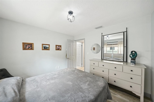 bedroom with light hardwood / wood-style floors and a textured ceiling