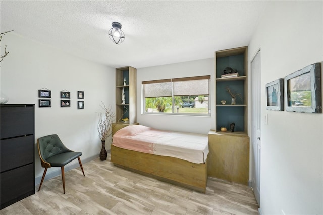 bedroom featuring light hardwood / wood-style floors and a textured ceiling