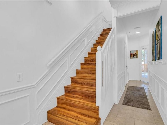 stairs with tile patterned flooring and ornamental molding