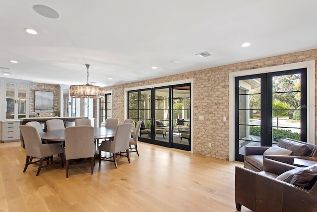 dining space featuring an inviting chandelier, french doors, and light wood-type flooring