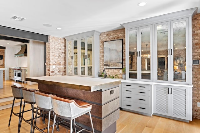 bar with premium range hood, light hardwood / wood-style floors, high end stove, and gray cabinetry