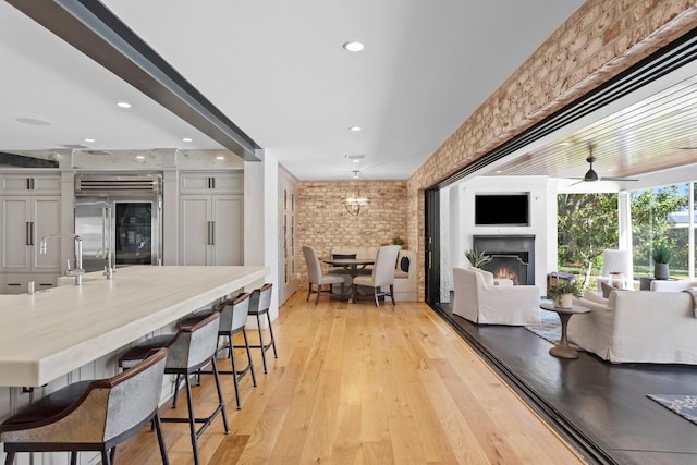 kitchen featuring sink, a breakfast bar, white cabinetry, brick wall, and built in fridge