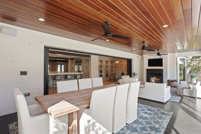 dining room featuring wood ceiling, brick wall, and a fireplace