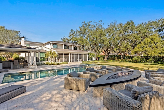 view of swimming pool with a patio, exterior bar, a sunroom, and a fire pit