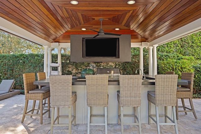 view of patio / terrace with an outdoor kitchen, ceiling fan, and a bar