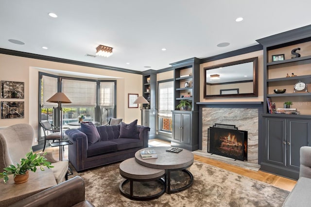 living room with a fireplace, a wealth of natural light, light hardwood / wood-style floors, and ornamental molding