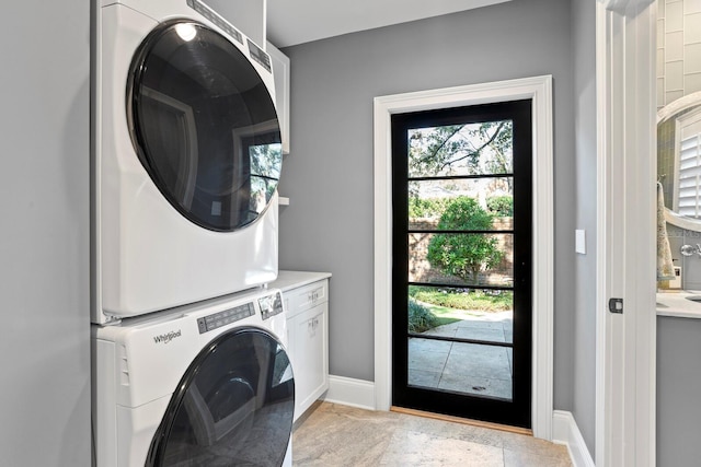 washroom with cabinets and stacked washer / drying machine